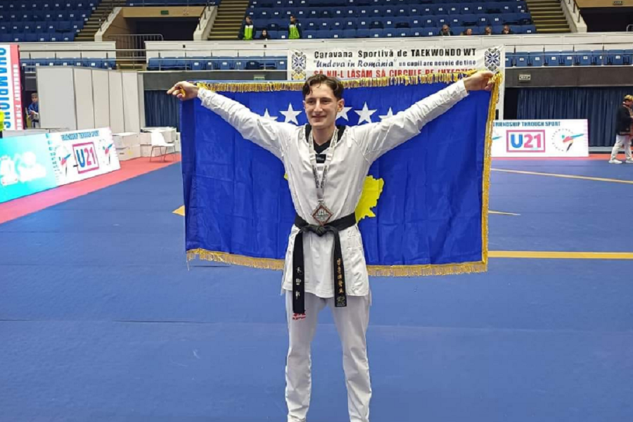 Bleron Ademi waves the Kosovo flag in the middle of Romania, runner-up of Europe in taekwondo